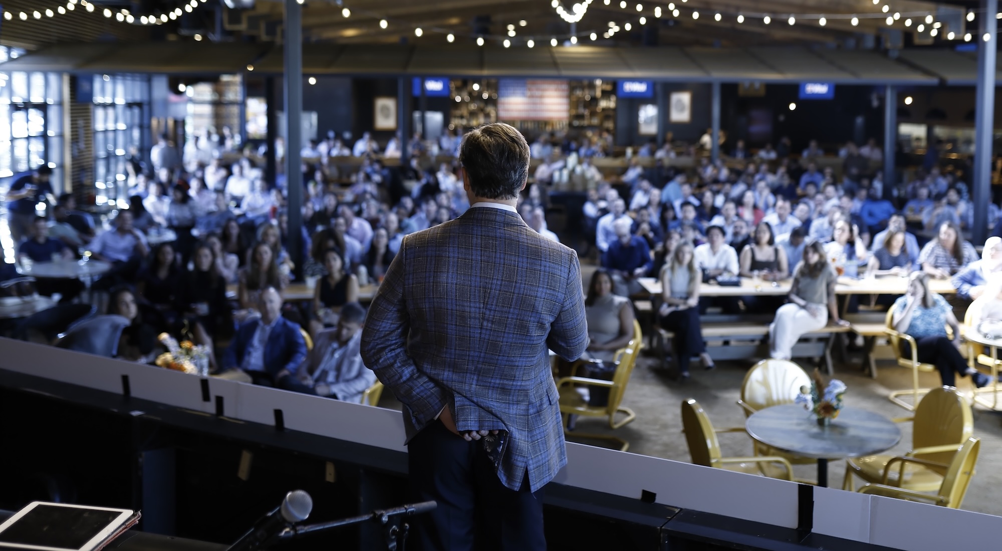 man presenting on stage to a large crowd